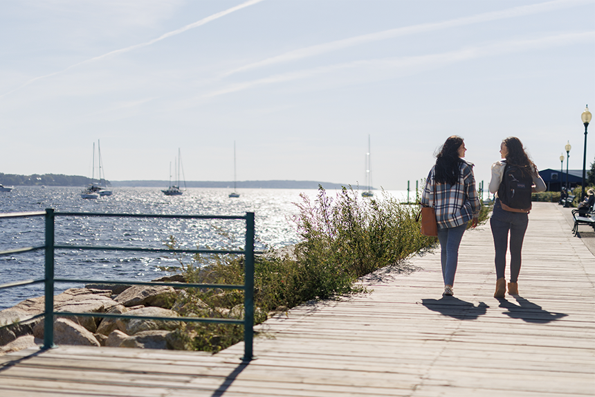 Two people walk along the Bristol harbor